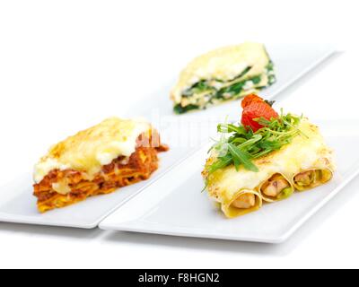 Close-up d'une lasagne traditionnelle faite avec du bœuf haché sauce bolognaise garnie de feuilles de basilic servi sur une plaque blanche Banque D'Images