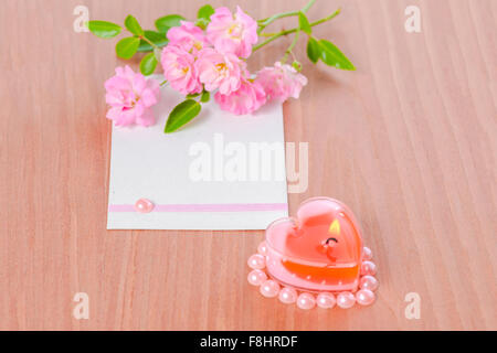 Carte de Saint Valentin en forme de coeur rose et bougie rose bouquet de fleurs sur fond de bois, gros plan Banque D'Images