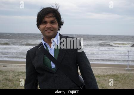 Un homme d'affaires sur la plage près de la mer avec du vent fort Banque D'Images