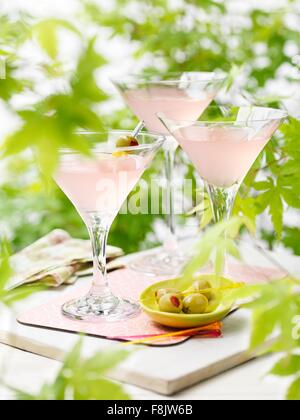 Trois verres de pamplemousse rose et des cocktails à base de martini aux olives vertes Banque D'Images
