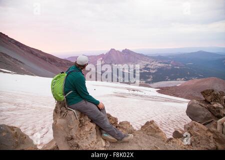 Jeune homme assis au sommet du volcan Sœur du Sud, Bend, Oregon, USA Banque D'Images