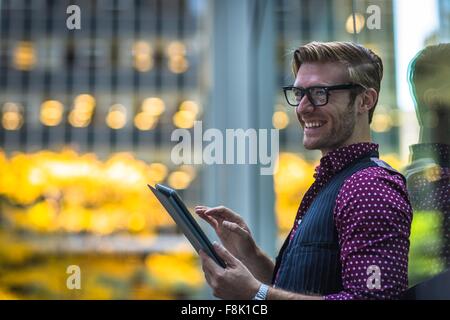 Happy young woman leaning against fenêtre parc using digital tablet Banque D'Images