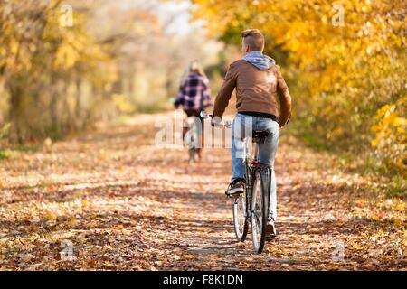 Vue arrière de l'adolescent et adulte soeur à vélo dans forêt d'automne Banque D'Images