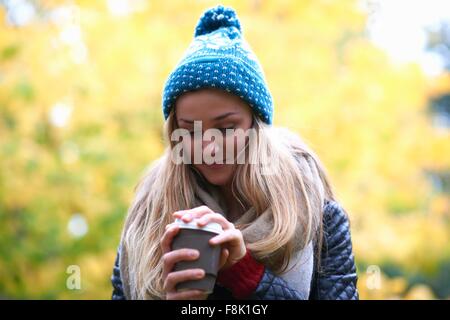 Jeune femme dépose couvercle de café à emporter dans la région de park Banque D'Images