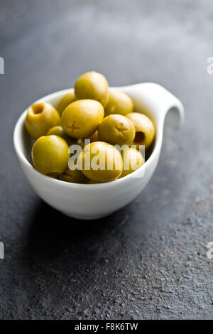 Olives vertes dénoyautées dans un bol sur le tableau noir Banque D'Images