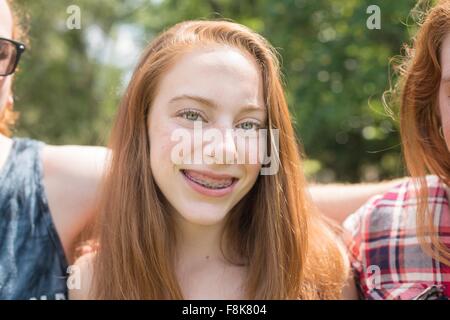 Portrait de jeune femme aux cheveux rouge avec appareil dentaire smiling at camera Banque D'Images