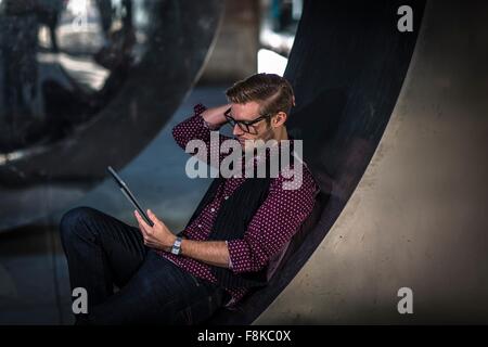 Young Woman reclining on mur incurvé lecture digital tablet Banque D'Images