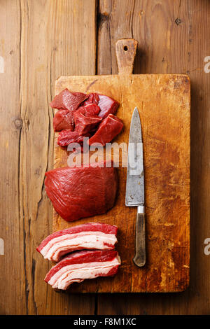 Différents types de matières de la viande fraîche et le couteau sur la planche à découper bloc sur fond de bois Banque D'Images