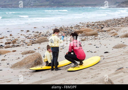 Un instructeur et deux jeunes surfeurs mâles apprendre à surfer sur des planches de surf sur la plage de Sennen Cove Cornwall England UK Banque D'Images