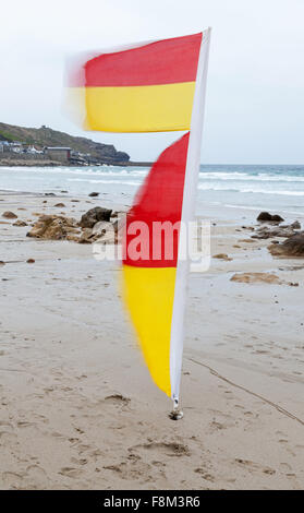 Drapeaux rouges et jaunes de marquer des zones qui sont surveillées par des sauveteurs et sont les plus sûrs endroits pour nager sur Sennen Cove Cornwall UK Banque D'Images