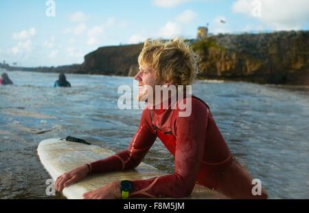 Surfer en mer, mâle holding surfboard, reposant Banque D'Images
