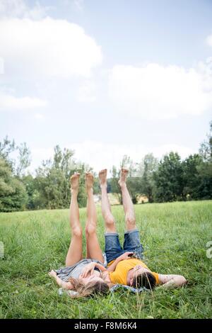 Jeune couple lying in field, les jambes soulevées Banque D'Images