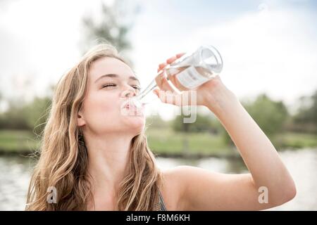 Jeune femme à boire l'eau de bouteille, à l'extérieur Banque D'Images