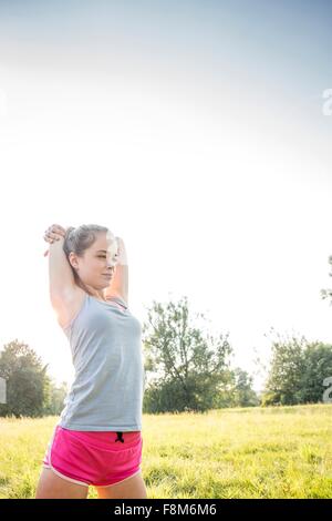 Young woman exercising, stretching, dans le champ Banque D'Images