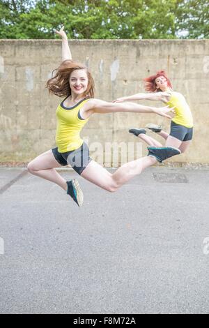Les jeunes femmes de sauter devant un mur de béton Banque D'Images