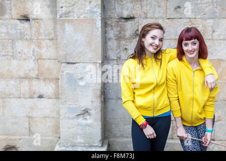 Young women smiling, mur en pierre en arrière-plan Banque D'Images