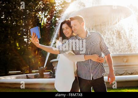 Couple sur selfies digital tablet in park Banque D'Images