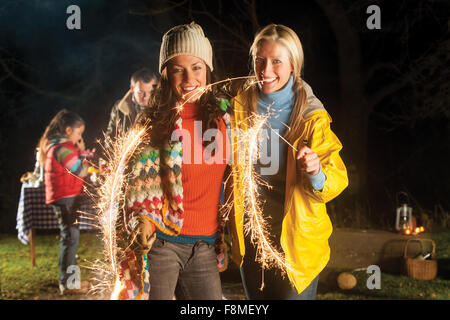 Deux femmes se tiennent ensemble en souriant pour l'appareil photo avec des cierges allumés dans leurs mains. Banque D'Images