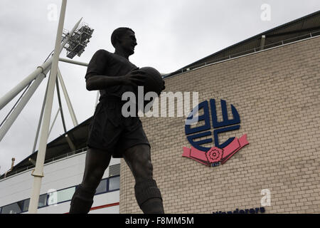 Bolton, Lancashire, UK. 10 Décembre, 2015. Bolton Wanderers, membres fondateurs de la Football League en 1888, ont été servis avec une liquidation pétition par Her Majesty's Revenue and Customs (HMRC) à la suite de son défaut de payer la TVA et autres taxes dues. Le club est quelque £178 millions de dollars de dettes et est présentement à la recherche d'un nouveau propriétaire. La statue de Bolton Wanderer's plus célèbre ancien joueur, Nat Lofthouse, se trouve à l'extérieur du stade Macron, éclipsé par des nuages sombres. Crédit : Joseph Clemson/Alamy Live News Banque D'Images