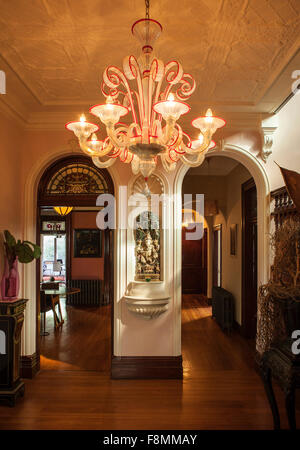 La maison d'Erica designer pols. La salle principale. Un grand lustre, dans des tons lumineux suspendus à un plafond en plâtre à motifs traditionnels. Parquet et deux arches menant dans une chambre et couloir. Banque D'Images