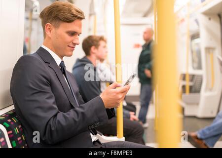 Businessman texting sur tube, le métro de Londres, UK Banque D'Images
