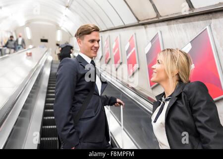 Businessman and businesswoman on escalator, métro de Londres, UK Banque D'Images
