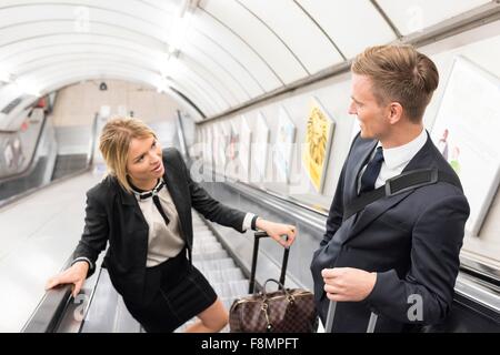 Businessman and businesswoman on escalator, métro de Londres, UK Banque D'Images