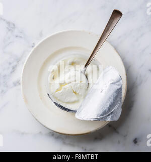 Le lait aigre Clabber dans boîte en plastique avec bouchon aluminium sur fond de marbre blanc Banque D'Images