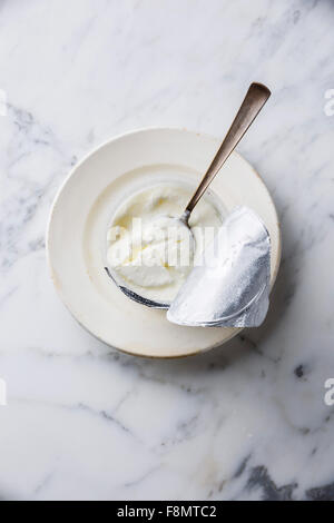 Le lait aigre Clabber dans boîte en plastique avec bouchon aluminium sur fond de marbre blanc Banque D'Images