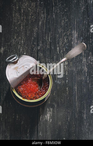 Ouvrir boîte de caviar rouge et cuillère en argent sur la surface en bois. Style rustique foncé. Vue d'en haut. Banque D'Images