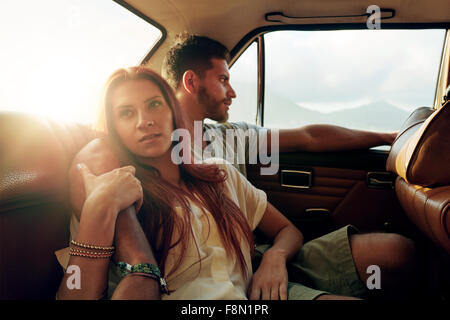 Coup de jeune femme avec son petit ami assis sur le siège arrière d'une voiture passe sur la route. Couple dans siège arrière de véhicule. Banque D'Images
