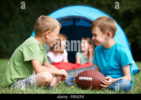 Deux garçons parler et jouer avec le football américain On camping Trip Banque D'Images