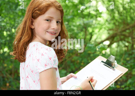 Girl Making Notes sur la sortie de la nature de l'école Banque D'Images