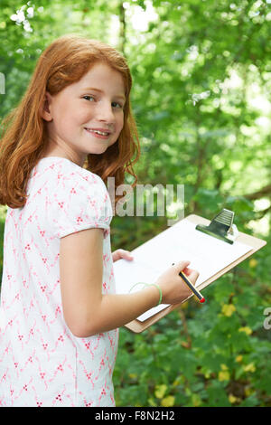 Girl Making Notes sur la sortie de la nature de l'école Banque D'Images