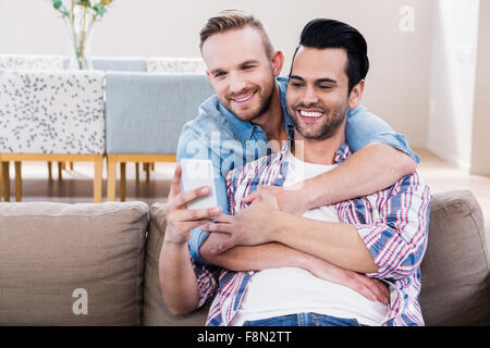 Couple Gay, se détendre sur la table à l'aide de téléphone Banque D'Images