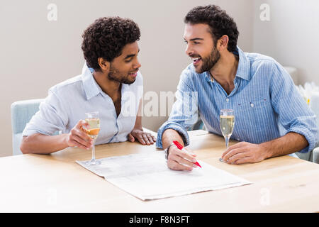 Happy gay couple drinking champagne et écrit le journal Banque D'Images