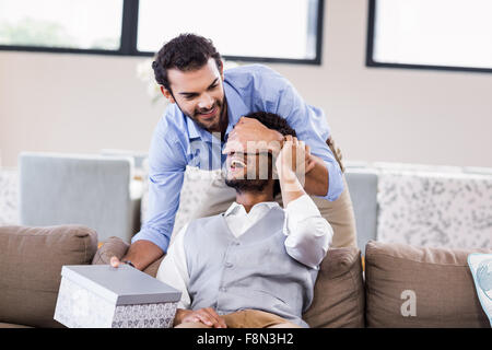 Bel homme couvrant les yeux de petits amis et donner un cadeau Banque D'Images