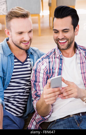 Couple Gay, se détendre sur la table à l'aide de téléphone Banque D'Images