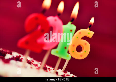 Quatre gros plan numéro allumé des bougies en forme de différentes couleurs formant le nombre 2016, comme la nouvelle année, sur un gâteau Banque D'Images