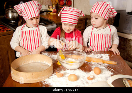 Trois petits chefs bénéficiant dans la cuisine faire grand désordre. Litt Banque D'Images