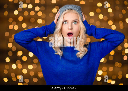 Portrait d'une femme blonde choqué pendant les vacances lumières fond permanent Banque D'Images