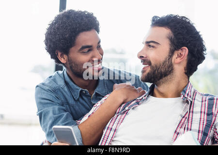 Heureux couple gay en conversation sur canapé Banque D'Images