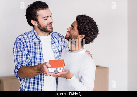 Happy gay couple holding miniature house model Banque D'Images