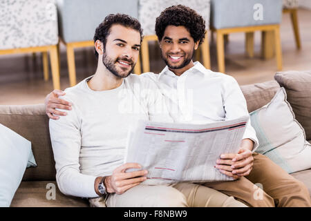 Happy gay couple reading newspaper Banque D'Images
