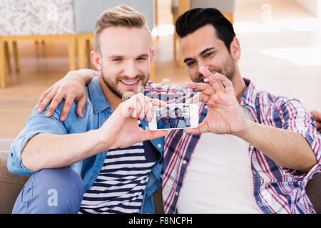 Couple Gay de détente sur le canapé en prenant selfies Banque D'Images