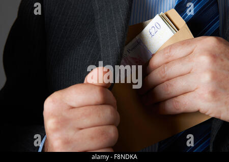 Businessman Putting Enveloppe de Sterling Notes dans une poche de veste Banque D'Images