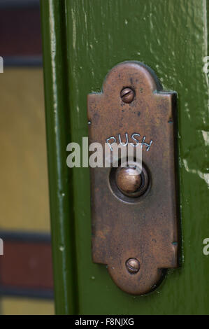 Vieux laiton terni, porte sur un mur vert Banque D'Images