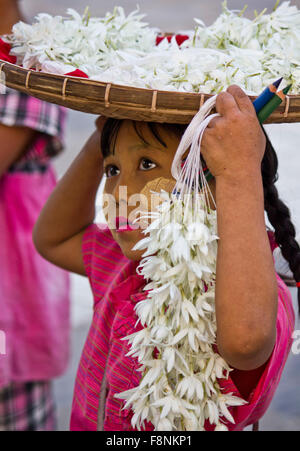 Jeunes Fleurs vendeur. Une jeune fille vend des fleurs dans la rue de Yangoon, au Myanmar (Birmanie) dans le visage qu'elle a le typique Banque D'Images