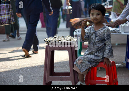 Sonnerie jeune vendeur. Une jeune fille vendant des cloches dans la rue de Yangoon, au Myanmar (Birmanie) dans le visage qu'elle a le sable typique Banque D'Images