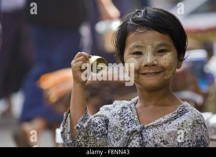 Sonnerie jeune vendeur. Une jeune fille vendant des cloches dans la rue de Yangoon, au Myanmar (Birmanie). Banque D'Images